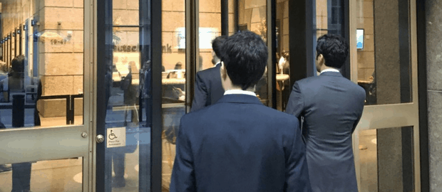 Profissionais de terno entrando em Deutsche Bank em Wall Street